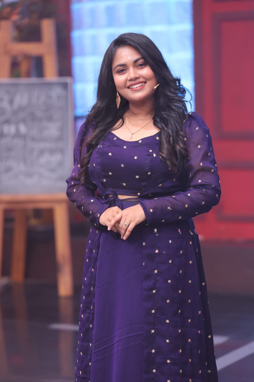Anu Anand smiling in a purple outfit